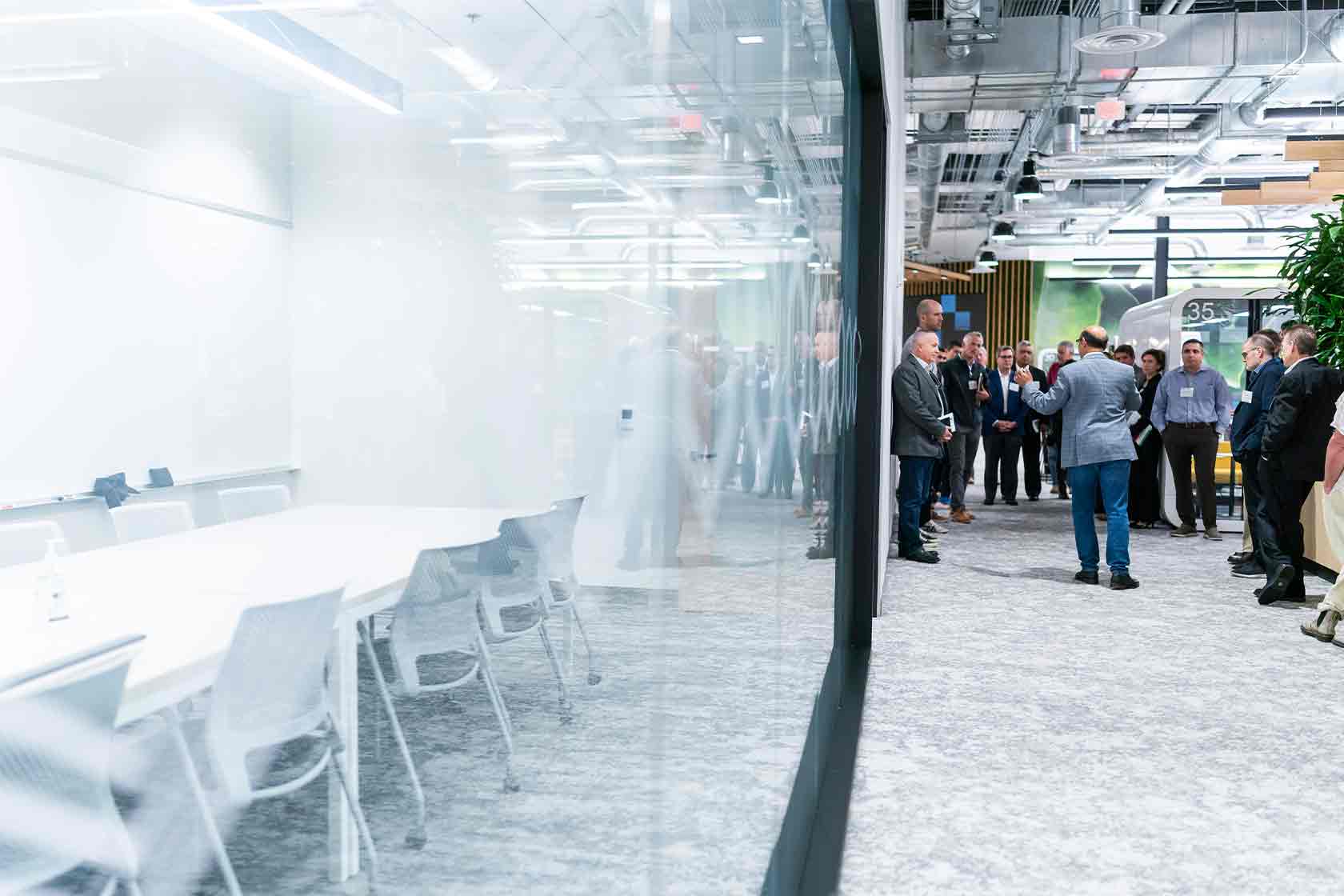 a split image of a conference room and people standing outside of the room chatting.