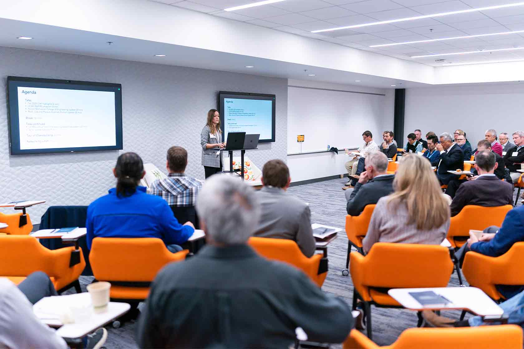 A woman talking at a podium in front of a seated audience.