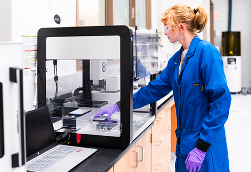 BioPACIFIC MIP lab assistant Marissa Beyer loads an automated robotic liquid handler inside the facility at OASIS.